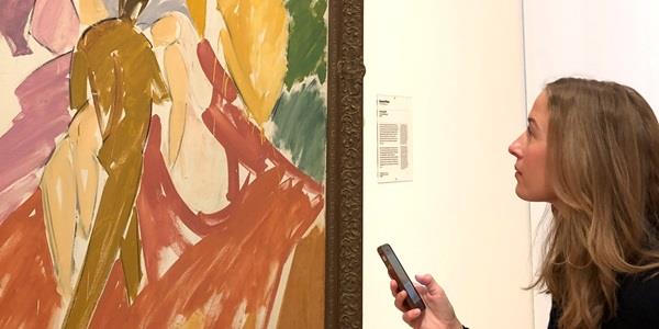 Woman looking at art with a smartphone in her hand